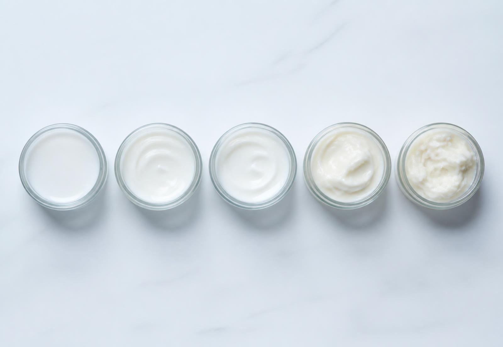 Five open jars showing successive versions of a cream, from thin to thick — illustrative imagery