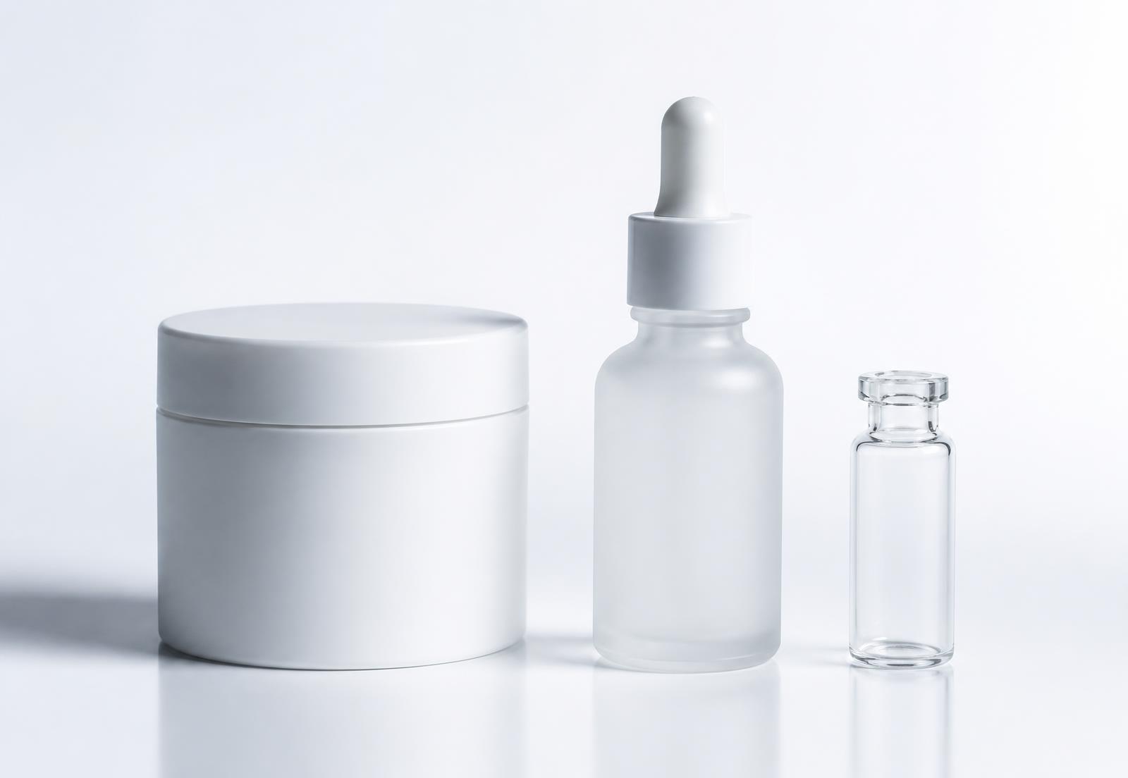 Three unlabelled prototype containers — a jar, a dropper bottle and a sample vial