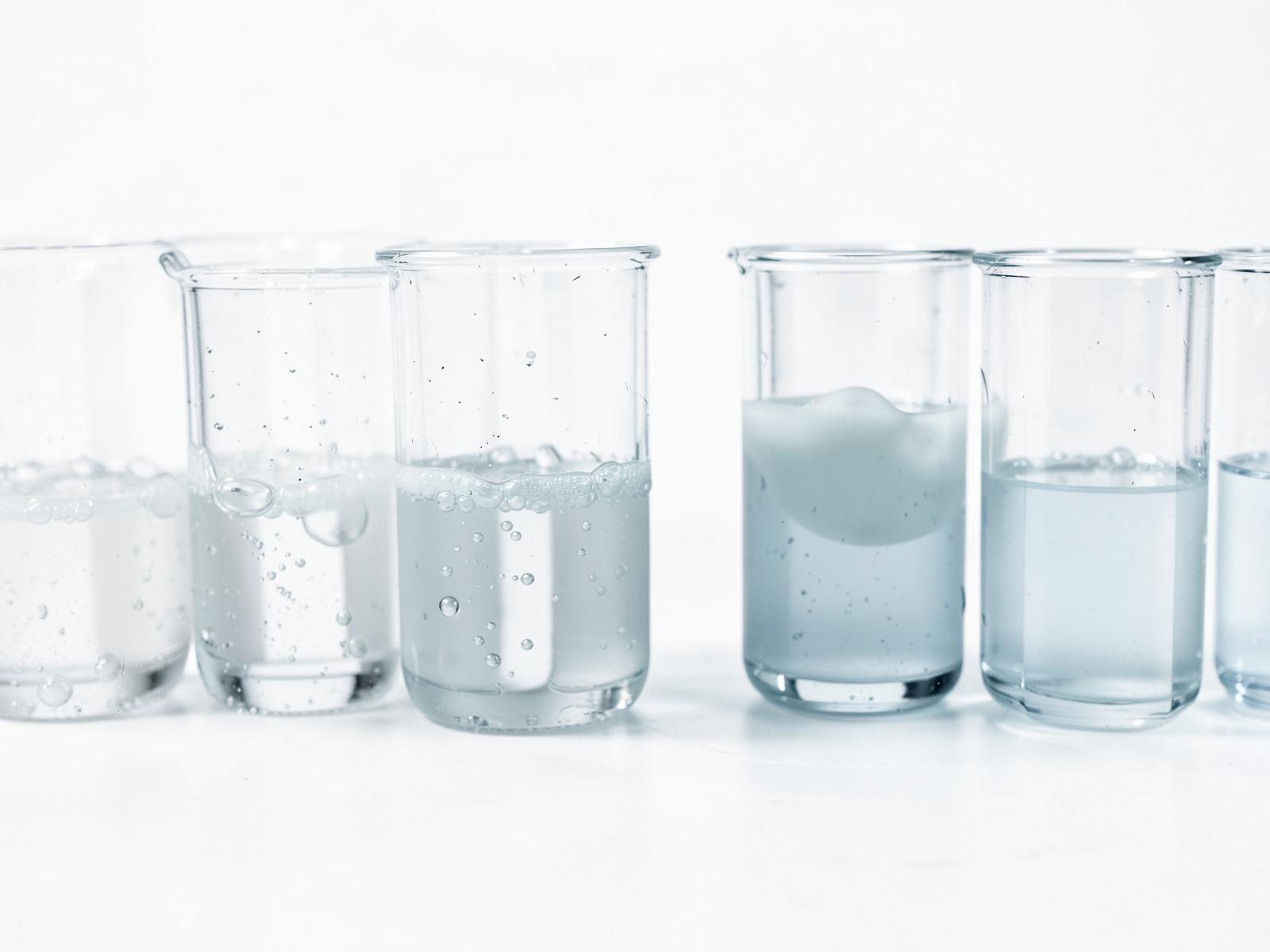 A row of beakers holding different clear and opaque preparations — illustrative imagery